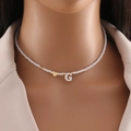 Dettaglio del ciondolo a lettera G e cuore dorato su collana di perline bianche - Lettera G
