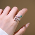 Anello serpente regolabile in argento con zircone verde smeraldo e pavé su una mano femminile - Anello Serpente Smeraldo Argentato (6974)