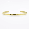 Detailed macro view of 4mm gold stainless steel cuff featuring BE STILL engraved text - BE STILL