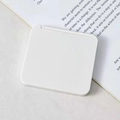Minimalist white square portable folding makeup mirror on a white book surface - White