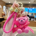 Pink resin bear keychain with knit texture, matching braided strap and golden bell detail - Sitting Knit Resin Bear-Rose Red