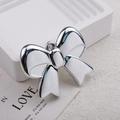 Glossy silver metallic bow pendant accessory for DIY jewelry making on white tray - Silver