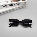 Flachbild von schwarzer ovaler Sonnenbrille auf Büchern vor hellem grauem Hintergrund - Schwarz