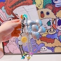 Gros plan d'un porte-clés en corde tressée avec étoile argentée et perles colorées - 44.A08 Grande Fleur Argentée