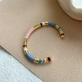 Macro detail of colorful enamel segments and gold metal base of the C-shaped cuff bracelet - Colorful