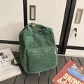 Minimalist green corduroy backpack for women with front pocket on a stylish grey bench - Green