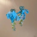 Dettaglio di orecchini a fiore in organza blu con perline a cuore e nappe di perline - Blu/Verde