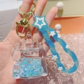 Close-up of blue glowing quicksand castle keychain with gold metal clasp and star strap - Castle Blue