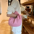 Pink leather knot handle crescent bag shown on model in a warm interior setting - Pink