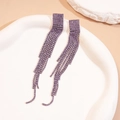 Detail of purple rhinestone fringe earrings displayed on a white textured stone base - Square / Purple