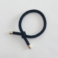 Macro detail of black braided elastic hair tie with polished gold metal cylinder buckle - Black