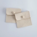 Two beige faux suede velvet jewelry pouches with snap button closure shown in flat lay - Beige