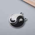 Makroansicht des Yin-Yang-Tai-Chi-Anhängers aus Metall mit schwarzen und silbernen Segmenten - Sonne Mond Tai Chi
