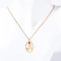 Detail of gold necklace with oval zodiac pendant and pink gemstone on white neck model - Leo