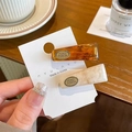 Set of two spring hair clips in amber and beige marble patterns held in hand - Amber + Cream White (Pair)