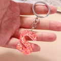 Detailed view of resin letter S keychain with vibrant orange sequins and metal ring - Letter S