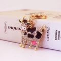 Cute cow keychain with sparkling crystals and black enamel on a gold metal frame - White