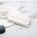 Minimalist white leather eyewear pouch with wrap-around tie closure on stone surface - White