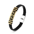 Detalle de pulsera de cuero trenzado negro con dije dorado y cierre de metal plateado - Latido del corazón