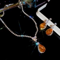 Macro di parure di gioielli argento con pietre preziose arancioni a goccia su sfondo nero - Set - Caffè
