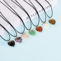 Multiple wire-wrapped heart crystal pendants in various gemstones on a white book base - White Crystal / Heart-Gold