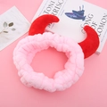 Gros plan d'un bandeau en peluche rose avec cornes de diable et texture douce - Rose Clair