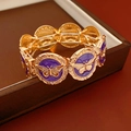 Detalle de pulsera dorada vintage con mariposas en esmalte violeta y motivos ornamentados - Mariposa Morada Dorada