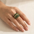 Detail of chunky gold ring with green crystals on a model hand with fabric background - US 6 / Green
