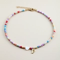 Macro shot of colorful beaded necklace featuring a white heart and golden letter P charm - Letter P