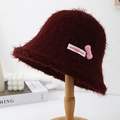 Detailed view of a fuzzy burgundy bucket hat featuring a sweet pink bow accessory - Burgundy