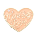 Close-up of pink heart enamel pin with More Self Love gold lettering and stars - More Self Love