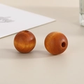 Close-up of two dark brown 16mm round wooden beads with natural grain and central holes - Translucent Light Coffee
