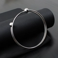 Detail of silver stainless steel open bangle with double ball ends on black fabric - Steel Color