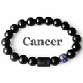 Detail view of black onyx bracelet featuring a blue accent bead and Cancer zodiac charm - Cancer