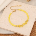 Detail of yellow natural stone beaded bracelet with gold lobster clasp on textured stone - Yellow