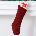 Red cable knit Christmas stocking with diamond pattern hanging by a fireplace - Dark Red