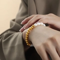 Baroque freshwater pearl and 18K gold-plated steel bracelet worn on a female wrist - Gold