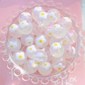Gros plan de perles acryliques lumineuses de 16mm avec motifs floraux blancs et jaunes - Frangipanier Frais / 16mm Lumineux