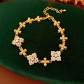 Nahaufnahme eines Vintage Gold-Blumenarmbands mit Zirkonia auf dunkelgrünem Samt - Gold-Klar