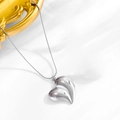Gros plan d'un pendentif cœur en argent poli sur soie blanche avec cadre doré - Collier Argent