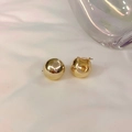 Dettaglio di orecchini a sfera dorati in stile minimalista francese su sfondo di stoffa - Oro