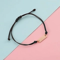 Detail of adjustable black braided rope bracelet with polished rose gold metal bar charm - Rose Gold Black Rope