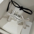 Detalle macro de pendientes de lazo de plata texturizada en una bolsa de joyería - Plateado