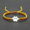 Detail of yellow braided rope bracelet with a polished silver paw print charm - Yellow