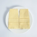 Detail of yellow microfiber jewelry pouches with flap closure on a white ceramic plate - Yellow