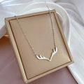 Close-up of minimalist silver reindeer antler pendant on delicate link chain over silk - Antler Shape (K322) / Silver