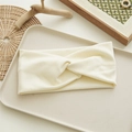 Detail of a creamy white knitted twist headband on a minimalist beige tray - Off-white