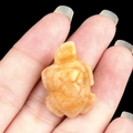 Mini yellow jade turtle carving held in palm showing natural gemstone texture and size - Topaz