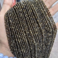 Faceted dark olive green stone beads with golden sheen layered on palm for crafts - Golden Obsidian 3mm