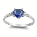 Detailed close-up of a silver heart ring featuring a large deep blue sapphire gemstone - Blue